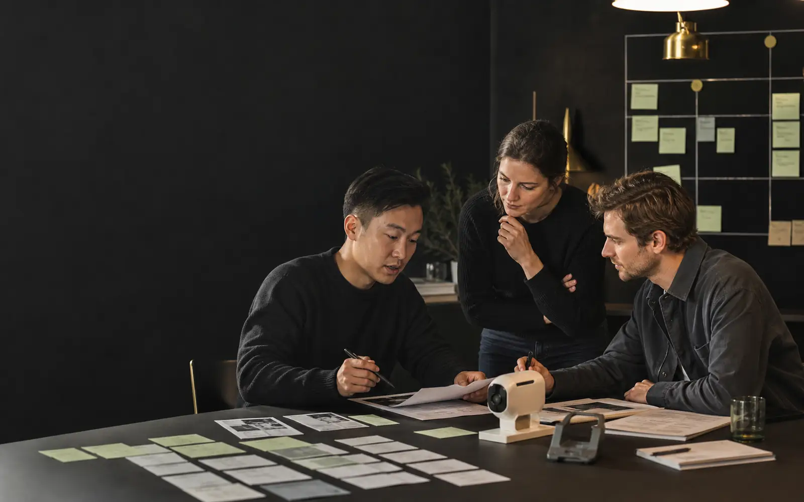Founders in a Vienna workspace reviewing interview notes and experiment cards on a dark wall